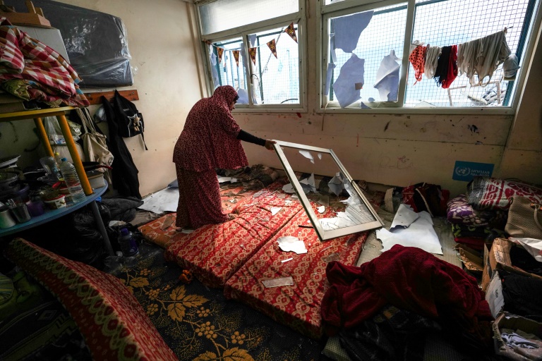 A woman checks a damaged room at a UNWRA school housing displaced Palestinians in Nuseirat, central Gaza