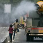 Children run behind a truck spraying water along a street on a hot summer day in New Delhi on Tuesday