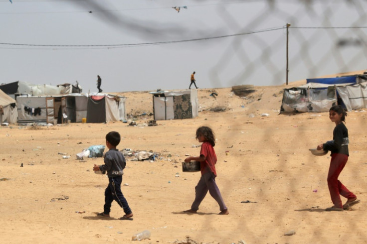 Displaced Palestinian children carry containers with food in the south Gaza city of Rafah, where a long-feared Israeli incursion is under way