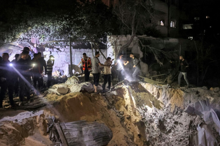 People search with flashlights by an impact crater at the site of a building that was hit by Israeli bombardment in Rafah in the southern Gaza Strip