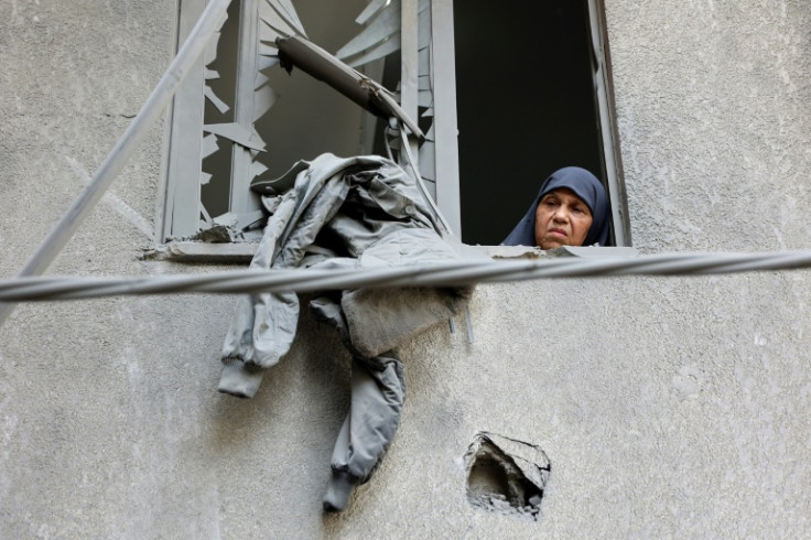 A woman looks out of the window of a bomb-damaged building in Gaza City
