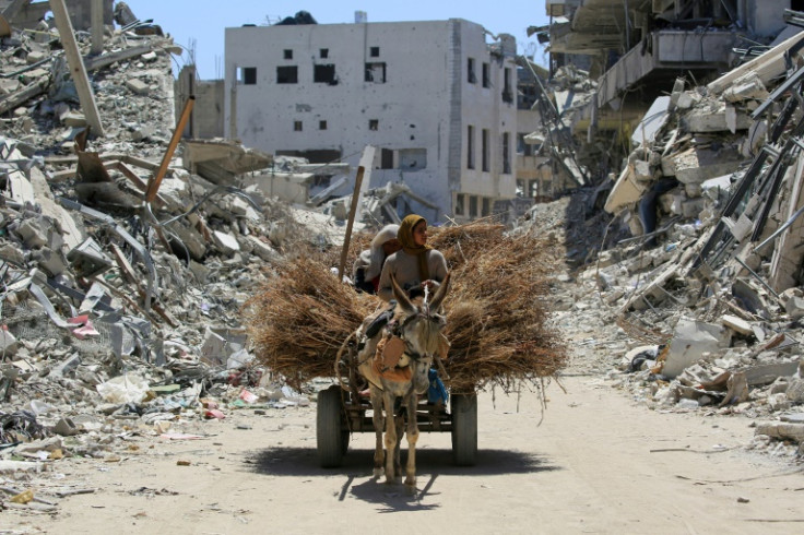 Women transport hay on a donkey-pulled cart along a devastated street in Khan Yunis in the southern Gaza Strip