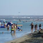Beachgoers frolic at Lady's Mile in Limassol, Cyprus, as a Eurofighter Typhoon lands at nearby Royal Air Force (RAF) base Akrotiri, on sovereign British territory
