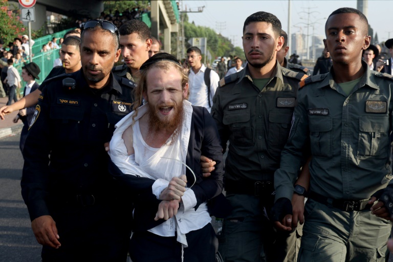 Israeli police detain a man as they they try to disperse ultra-Orthodox Jews blocking a highway during a protest against possible changes regarding the laws on the military draft