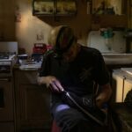Oleksandr, 67, repairs shoes in his kitchen during an electricity blackout