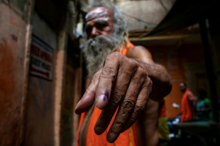 A Hindu priest shows his indelible ink mark after casting his vote at a polling station