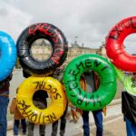 Protesters hold inflatable tubes in Olympic colors