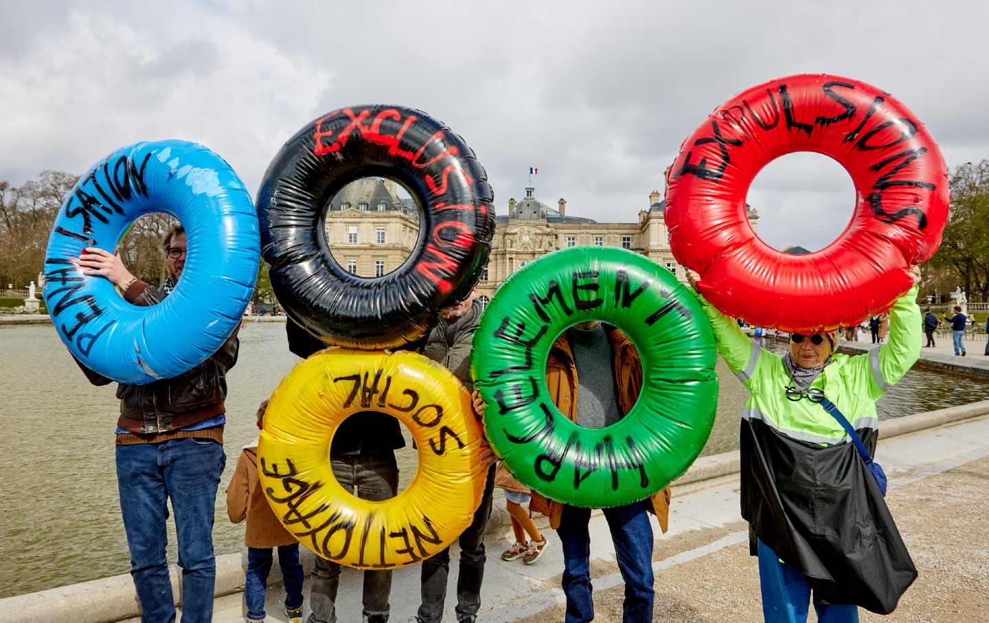 Protesters hold inflatable tubes in Olympic colors