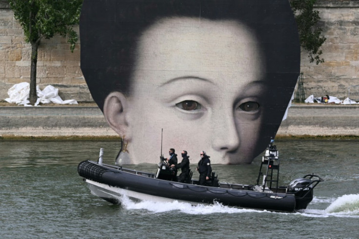 Police patrol the river Seine in front of a prop for the Olympic opening ceremony