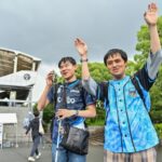Mashiro (L) cheering with his friend after they arrive at a stadium using an app with ChatGPT for directions
