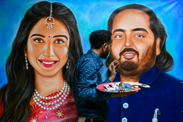 An artist paints portraits of Radhika Merchant (L) and her fiance Anant Ambani, son of billionaire Mukesh Ambani, ahead of their wedding