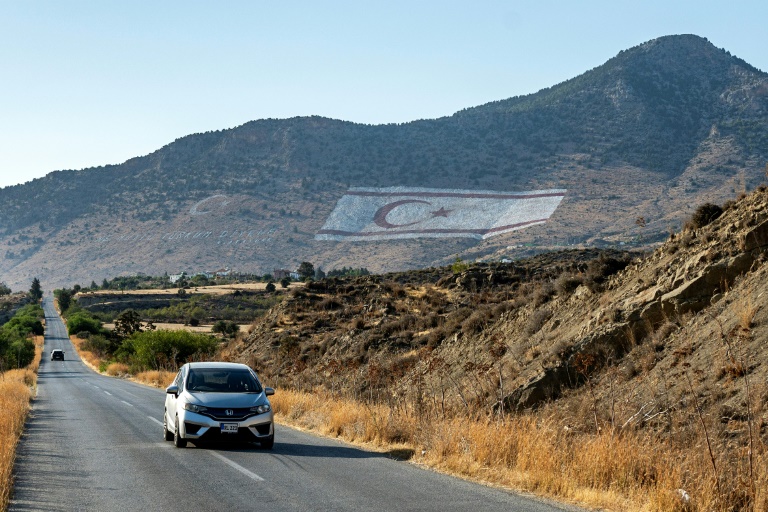 A motorist drives a car near the giant flag of the self-proclaimed Turkish Republic of Northern Cyprus