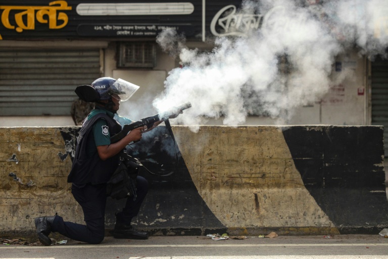 A Bangladesh policeman fires tear gas shells at protesters during clashes in Dhaka