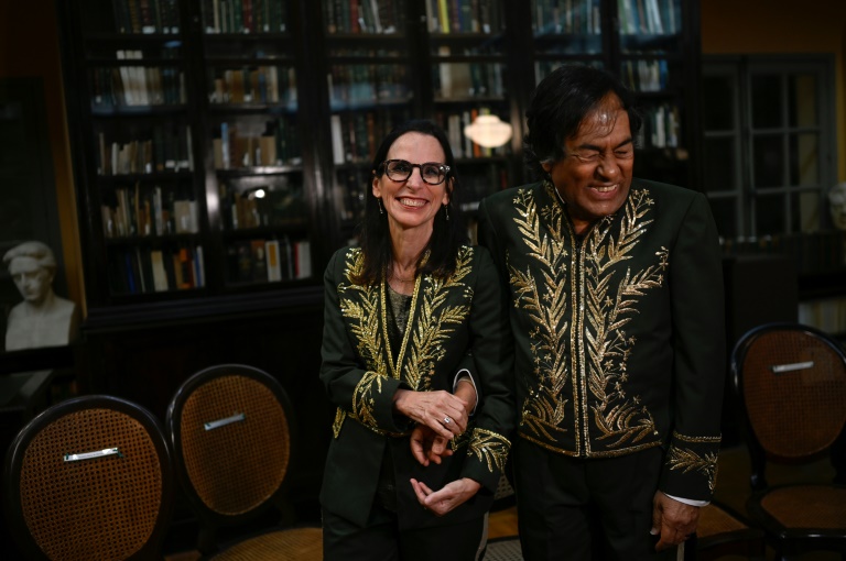 Brazilian Indigenous writer Ailton Krenak (R) and historian Lilia Schwarcz (L) hold hands during the swearing-in ceremony