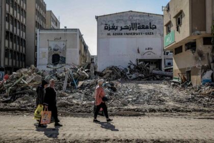 Palestinians walk next to the remains of Al-Azhar University in Gaza City on February 10, 2024.