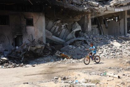 A Palestinian boy cycles past buildings destroyed in previous Israeli bombardment, in the Sheikh Radwan neighbourhood, north of Gaza City on July 3, 2024