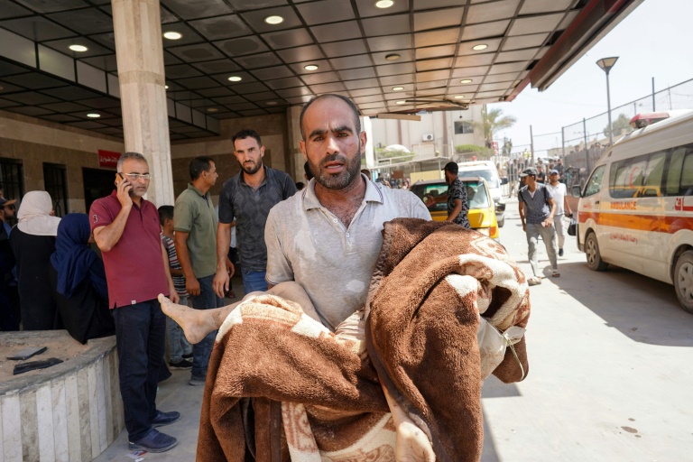 A man carries a child wrapped in a blanket at the Nasser hospital after Israeli strikes in the Khan Yunis area