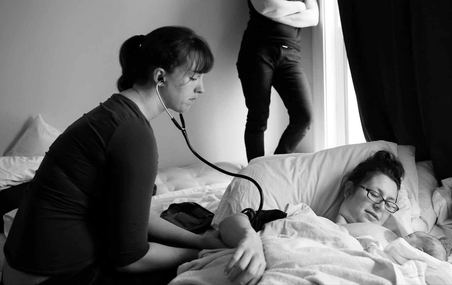 A student midwife taking a mother's blood pressure.