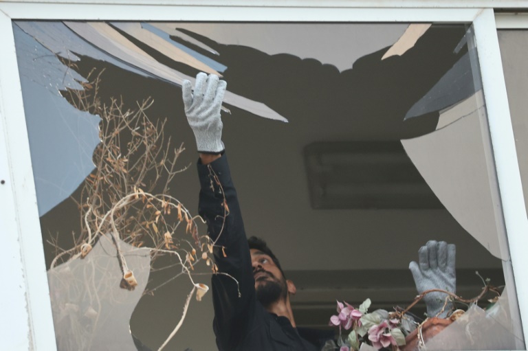 An Israeli policeman collects glass shrapnel from the window of a building that was damaged in an explosion in Tel Aviv