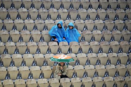 Wet, wet, wet: Spectators sit in the stands as the rain falls