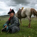 Luvsanbaldan Batsukh rests next to his horse after herding sheep and goats in Khishig-Undur in Bulgan province