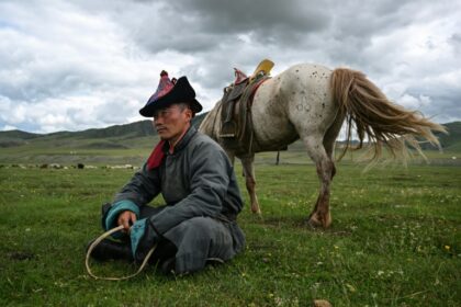 Luvsanbaldan Batsukh rests next to his horse after herding sheep and goats in Khishig-Undur in Bulgan province