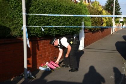 A police officer lays floral tributes at the site of the attack