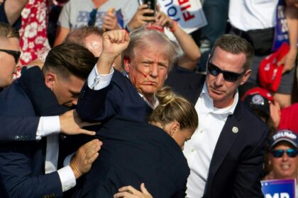 A woman Secret Service agent can be seen helping to bundle a bloodied Donald Trump from the stage after an assassination attempt in Pennsylvania on July 13
