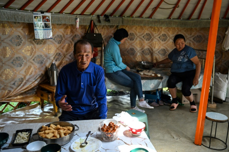 Bat-Ulzii Bat-Erdene (L), the father of financial consultant Bat-Erdene Khulan (C) who now lives in the capital Ulaanbaatar, talks while his wife Sanduijav Altakhuyag (R) prepares lunch with their daughter inside a ger in Batsumber in Tuv province