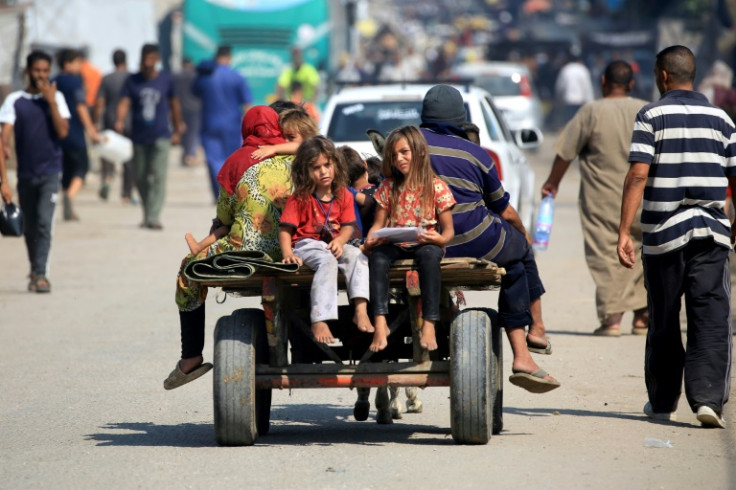Displaced Palestinians ride in the back of a donkey-drawn cart in Deir el-Balah