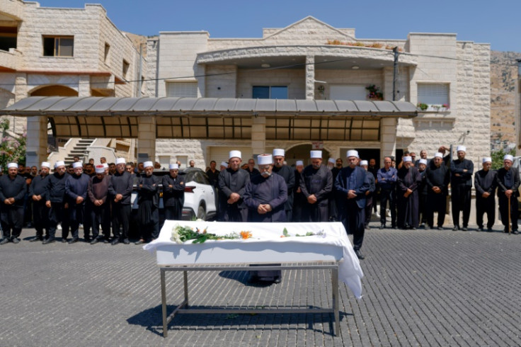 Druze elders and mourners pray by the coffin of Guevara Ibrahim, 11, killed by rocket fire on the Israeli-annexed Golan Heights