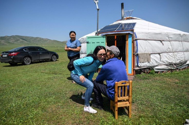 Financial consultant Bat-Erdene Khulan, who now lives in the capital Ulaanbaatar, greets her parents Bat-Ulzii Bat-Erdene (R) and Sanduijav Altakhuyag outside their ger in Batsumber in Tuv province