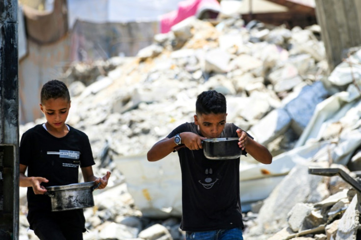 Palestinian boys carry pots of donated food in Nuseirat, central Gaza -- the war has left the vast majority of Gazans displaced