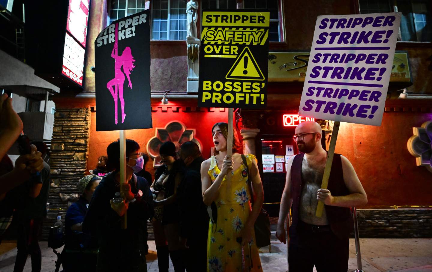 Protesters hold signs reading 