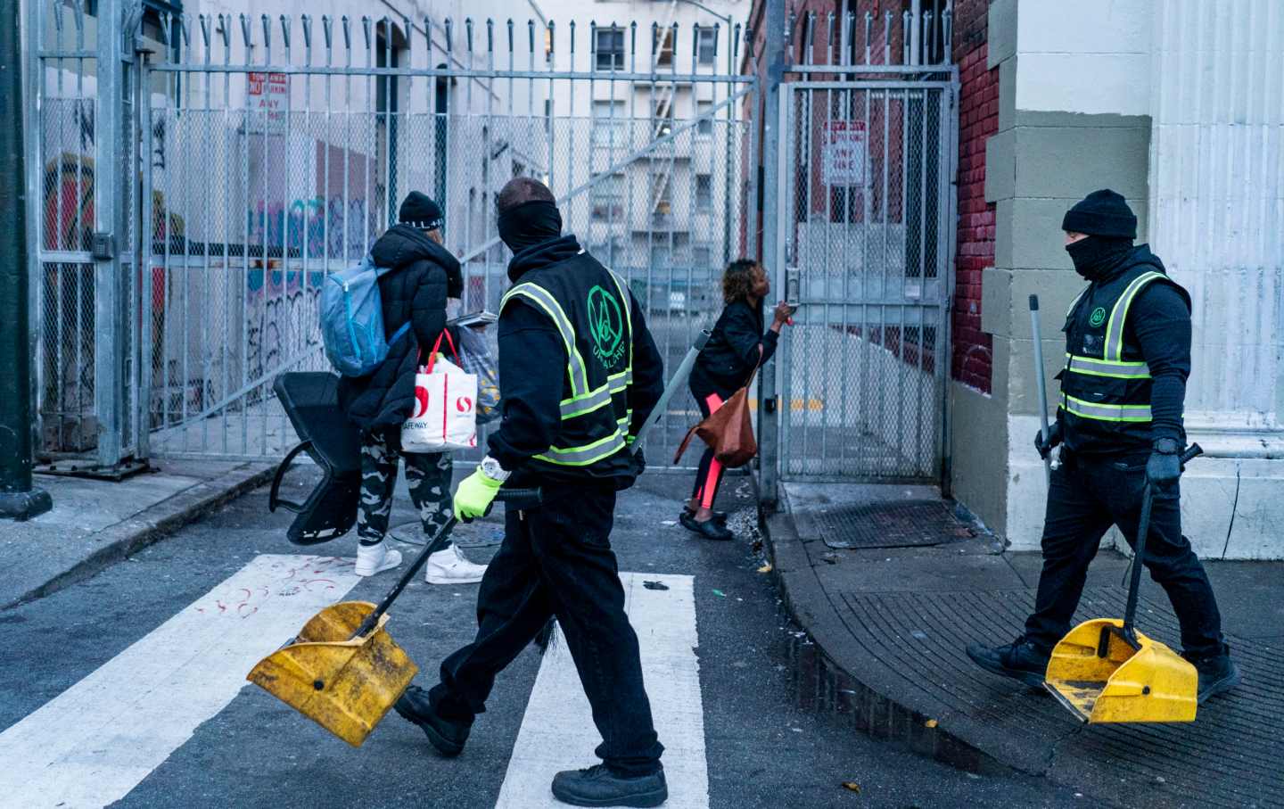 A homeless man and woman quickly pick up their belongings as Urban Alchemy crews begin their daily cleaning of the streets in the Tenderloin neighborhood of San Francisco on January 26, 2022.