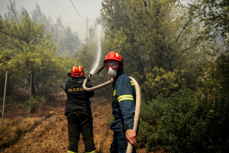 Firefighters hosing a wildfire in Dione outside Athens