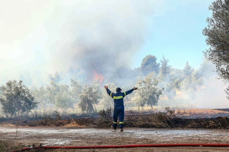 A firefighter coordinates the fight against a wildfire that has forced the evacuation of thousands of people around Athens