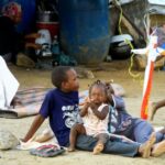 People rest at a makeshift camp after being evacuated due to deadly floods in eastern Sudan