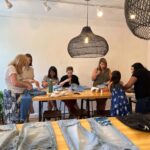 Textile artist Sophie Canter (2L) teaches a "Mending 101" workshop in the Georgetown neighborhood in Washington, DC on August 3, 2024.   Activities and crafts focusing on low-consumption are gaining popularity on and offline amid financial hardship and pu