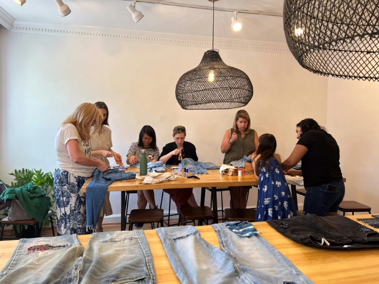 Textile artist Sophie Canter (2L) teaches a "Mending 101" workshop in the Georgetown neighborhood in Washington, DC on August 3, 2024.   Activities and crafts focusing on low-consumption are gaining popularity on and offline amid financial hardship and pu