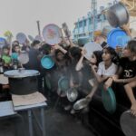 Displaced Palestinian children queue to receive food distributed by aid organizations in Beit Lahia, Gaza, on July 18, 2024.