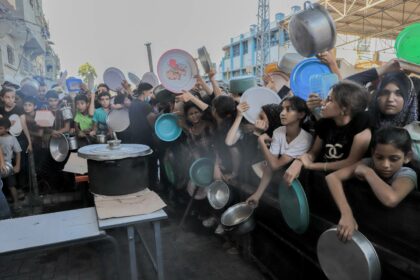 Displaced Palestinian children queue to receive food distributed by aid organizations in Beit Lahia, Gaza, on July 18, 2024.