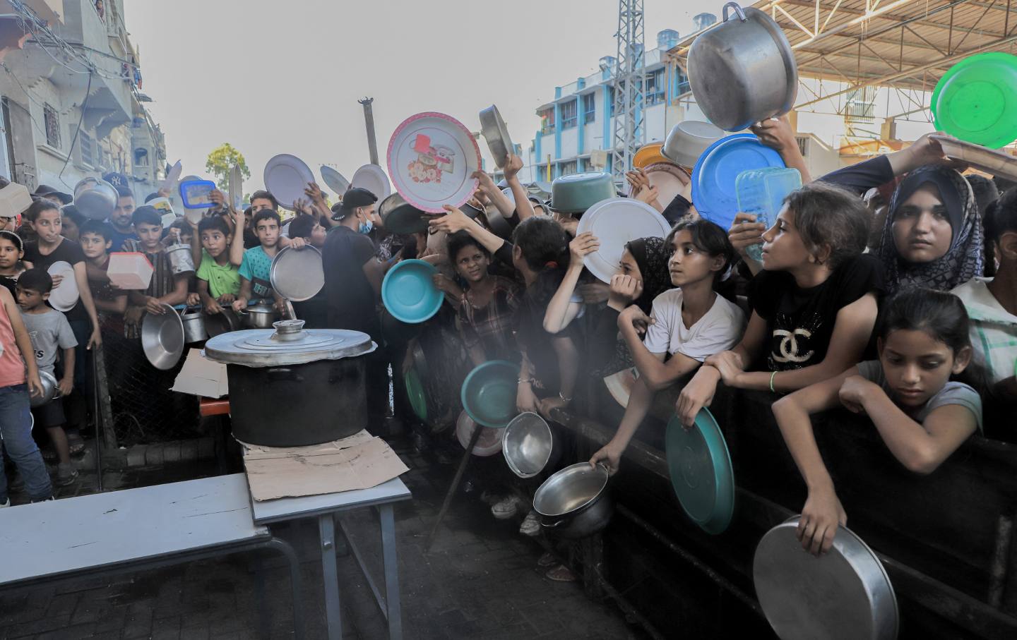 Displaced Palestinian children queue to receive food distributed by aid organizations in Beit Lahia, Gaza, on July 18, 2024.