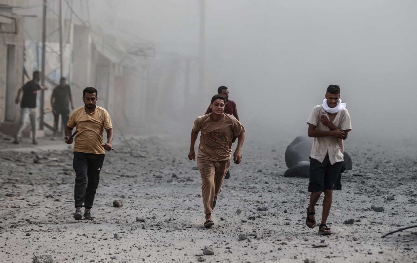 Palestinians try to get away from the area as smoke and dust rise following the Israeli army attack a building in the Nuseirat Refugee Camp in Deir al-Balah, Gaza,