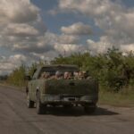 Around 10 blindfolded and bound men in Russian military fatigues being driven in a military vehicle away from the border crossing in the direction of the city of Sumy