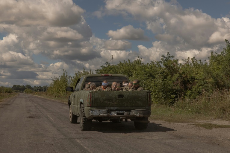 Around 10 blindfolded and bound men in Russian military fatigues being driven in a military vehicle away from the border crossing in the direction of the city of Sumy