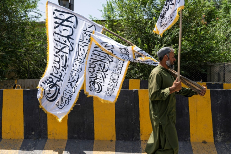 An Afghan man sells Taliban flags along a Kabul street on the eve of the third anniversary of Taliban takeover of Afghanistan