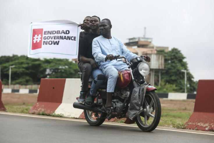 Demonstrators carry a banner from their motorcycle while demonstrating in Abuja