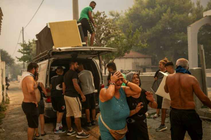 Residents cry as they try to save belongings from homes in Penteli, one of the Athens suburbs worst hit by a wildfire that forced the evacuation of thousands of people