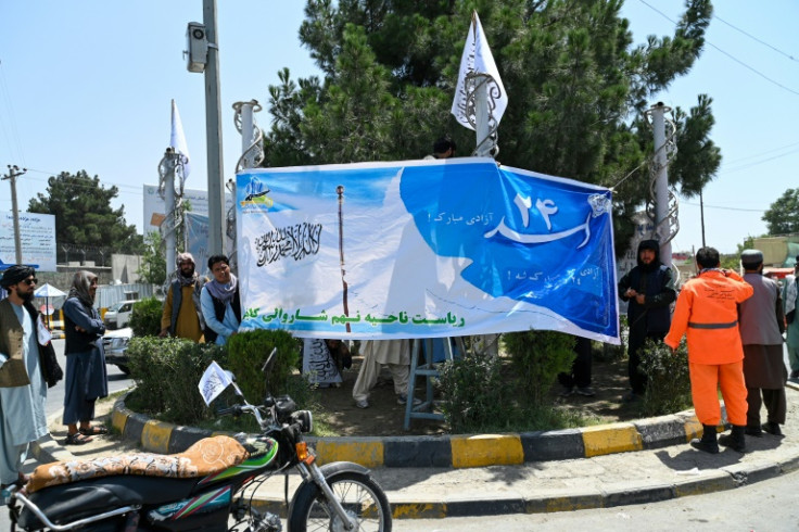 Taliban and municipal workers install banners at a Kabul square on the eve of the third anniversary of Taliban takeover of Afghanistan